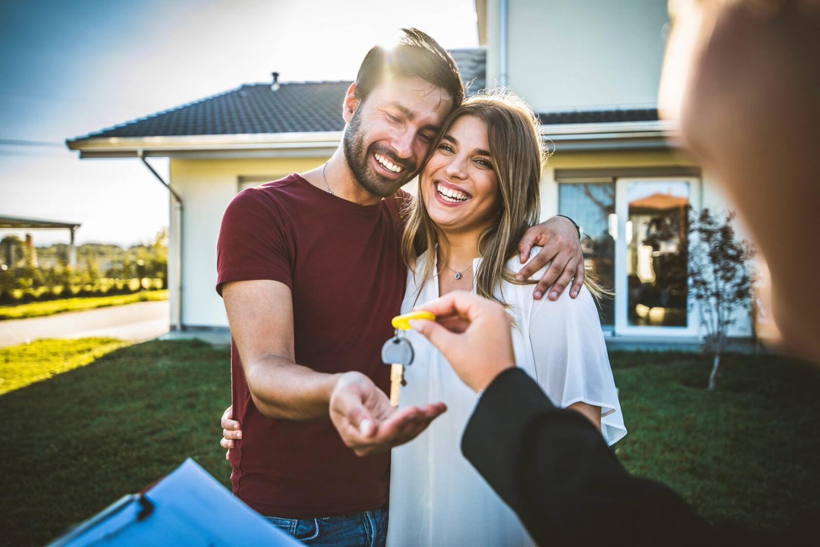 Happy millennial doctors receiving house keys from their realtor